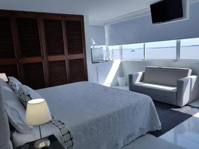 a bedroom with a bed and a chair and a television at Espectaculares Vistas, Edificio Nautilus, Barrio El Laguito. in Cartagena de Indias