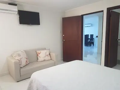 a bedroom with a bed and a couch and a tv at Espectaculares Vistas, Edificio Nautilus, Barrio El Laguito. in Cartagena de Indias