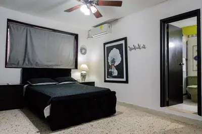 a bedroom with a black bed and a ceiling fan at Casa Gaitán Beach and comfort by the sea in Cartagena de Indias
