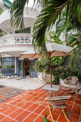 a patio with chairs and an umbrella in front of a building at Casa Gaitán Beach and comfort by the sea in Cartagena de Indias