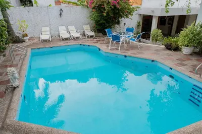 a blue swimming pool with chairs and a table at Casa Gaitán Beach and comfort by the sea in Cartagena de Indias