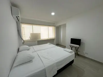 a bedroom with a bed and a laptop on a desk at Apartamento Moderno con Piscina en el Laguito in Cartagena de Indias