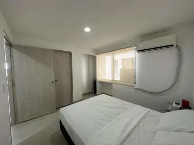 a bedroom with a white bed and a window at Apartamento Moderno con Piscina en el Laguito in Cartagena de Indias