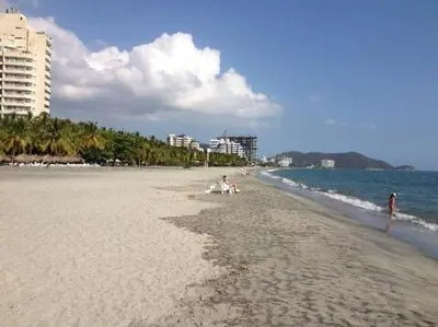 a beach with people sitting on the sand and the ocean at Bello Horizonte y CC ZAZUE in Santa Marta