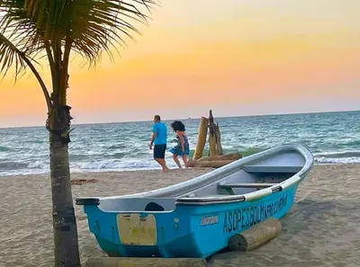 a blue boat sitting on the beach with a palm tree at Escapada Perfecta en Apartasuites Privadas Coveñas in Coveñas