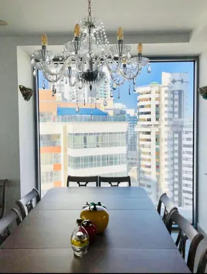 a dining room table with a chandelier and a large window at Luxurious and modern oceanfront apartment with views of the historic city 2B and 2BR in Cartagena de Indias