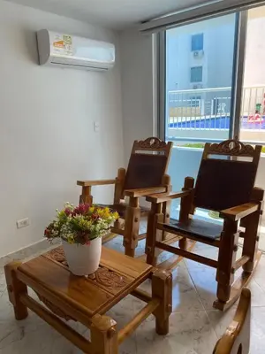 two wooden chairs and a table with a vase of flowers at Acojedor apto en coveñas in Coveñas