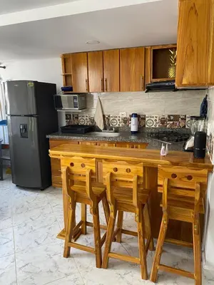 a kitchen with a wooden counter with chairs and a refrigerator at Acojedor apto en coveñas in Coveñas