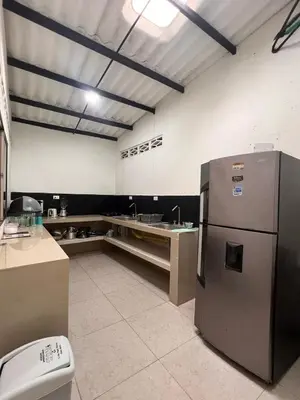 a large kitchen with a refrigerator and a sink at Villa Manglar in Coveñas