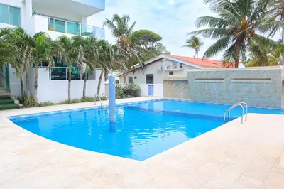a swimming pool in front of a house with palm trees at Magico Apartamento Frente al Mar 2 Habitaciones B11B in Coveñitas