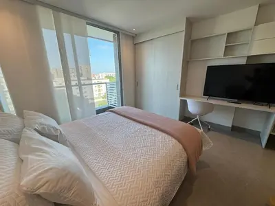 a bedroom with a large bed and a flat screen tv at Hermosa y Comoda Suite en Distrito 90 in Barranquilla