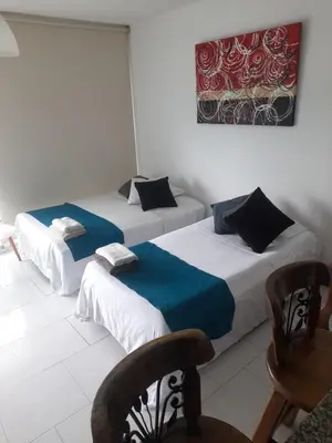 two beds in a room with chairs and a painting on the wall at Apartamento vista al mar cartagena Edificio Morros in Cartagena de Indias