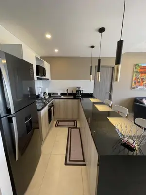 a kitchen with black counter tops and a refrigerator at Castelo - Serena Del Mar in Puerto Tierrabaja