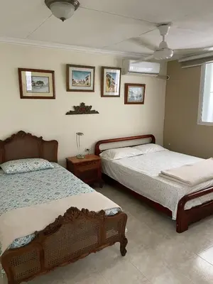 a bedroom with two beds and a table and pictures on the wall at Casa Estela in Cartagena de Indias