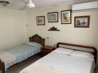 a bedroom with two beds and pictures on the wall at Casa Estela in Cartagena de Indias