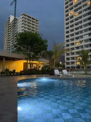 a swimming pool with two chairs and two tall buildings at Modern Apartment in Santa Marta in Santa Marta