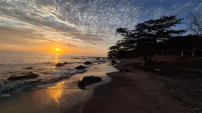 a sunset on a beach with the sun setting at Modern Apartment in Santa Marta in Santa Marta