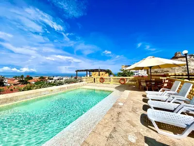 a swimming pool with chairs and an umbrella at by Calamari Homes - El Porvenir 207 walled city in Cartagena de Indias
