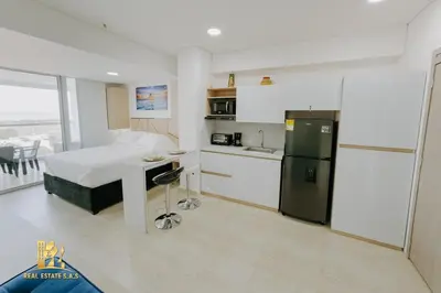 a bedroom with a bed and a kitchen with a refrigerator at Modern Apartasuit Cartagena Beach in Cartagena de Indias