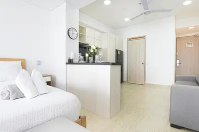 a white bedroom with a bed and a kitchen at Apartasuit Cartagena luxury 1240 in Cartagena de Indias