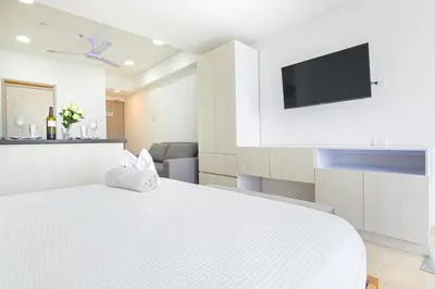 a white bedroom with a large bed and a flat screen tv at Apartasuit Cartagena luxury 1240 in Cartagena de Indias