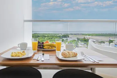 a table with two plates of food and two glasses of orange juice at Luxurious Apartasuit CartagenaBeach1139 in Cartagena de Indias