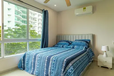 a bedroom with a bed with a blue comforter and a window at Exclusivo apartamento de lujo frente al mar en Los Morros, con acceso directo y privado a la mejor playa de Cartagena in Cartagena de Indias