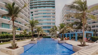 a swimming pool with palm trees in front of a building at Beachfront Condo in Cartagena in Cartagena de Indias