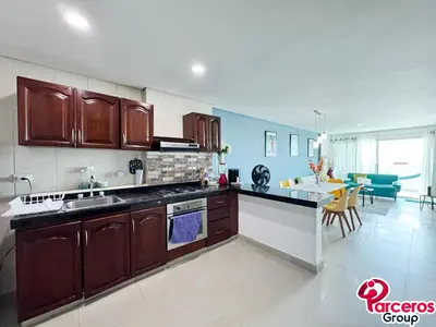 a kitchen with wooden cabinets and a living room at Apartamentos Torres Del Lago Por Parceros Group in Cartagena de Indias