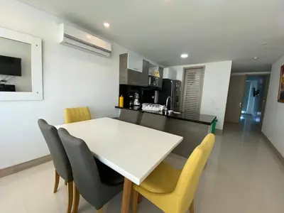 a kitchen and dining room with a white table and chairs at Apartamentos Palmetto Sunset por Parceros Group in Cartagena de Indias