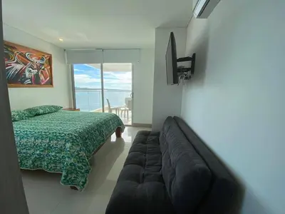 a bedroom with a bed and a couch and a window at Apartamentos Palmetto Sunset por Parceros Group in Cartagena de Indias