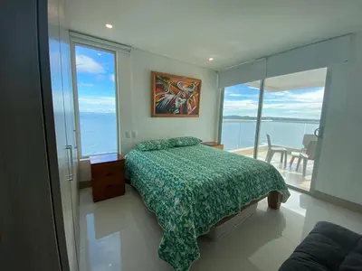 a bedroom with a bed and a view of the ocean at Apartamentos Palmetto Sunset por Parceros Group in Cartagena de Indias