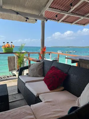 a couch on a deck with the ocean in the background at Hotel Los Chamos Barú in Cartagena de Indias