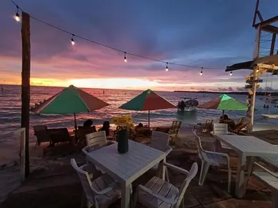 a table and chairs on the beach at sunset at Hotel Los Chamos Barú in Cartagena de Indias