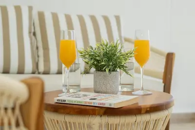 two glasses of orange juice and a book on a table at Seaside Serenity and Style in Cartagena de Indias