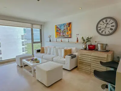 a living room with a white couch and a clock at Hotel Radisson Residences Ocean Pavillion in Cartagena de Indias