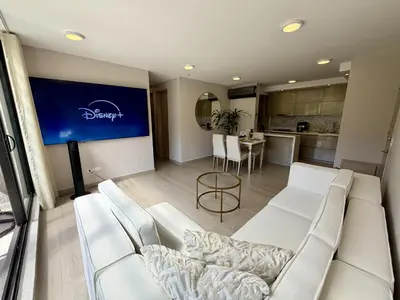 a living room with white furniture and a kitchen at Luxury loft with home theater & pool, Buenavista top location in Barranquilla