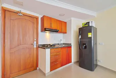 a kitchen with a black refrigerator and wooden cabinets at Espectacular vista piso 20 in Cartagena de Indias