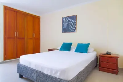 a bedroom with a large white bed and a wooden cabinet at Espectacular vista piso 20 in Cartagena de Indias