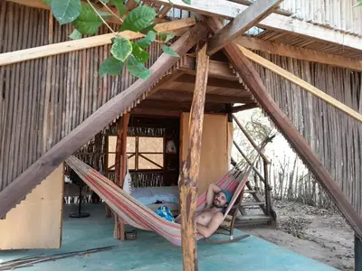 a woman laying in a hammock in a house at Casa Surya - Cabaña sostenible en la naturaleza in San Onofre