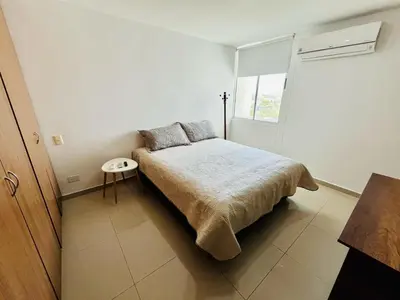 a white bedroom with a bed and a window at Apartamento en Sabanilla in Puerto Colombia
