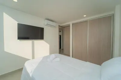 a bedroom with a white bed with a flat screen tv at Premium Hub Ocean View Apartment in Cartagena 905 in Cartagena de Indias