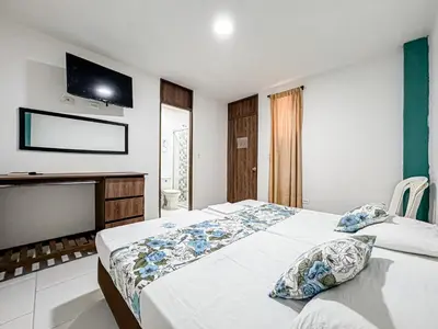 a bedroom with two beds and a flat screen tv at Hotel Santiago de Tolú in Santiago