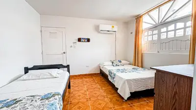 two beds in a small room with a window at Hotel Santiago de Tolú in Santiago