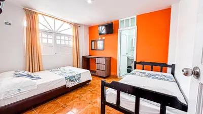 two beds in a room with orange walls at Hotel Santiago de Tolú in Santiago