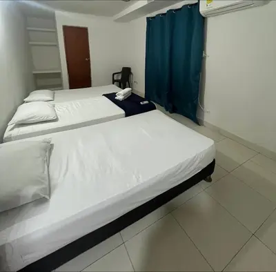 two beds in a room with a blue curtain at Stay Mar y Playa House in Cartagena de Indias