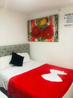 a red blanket on a bed with a painting on the wall at Hotel Altos del Prado in Barranquilla