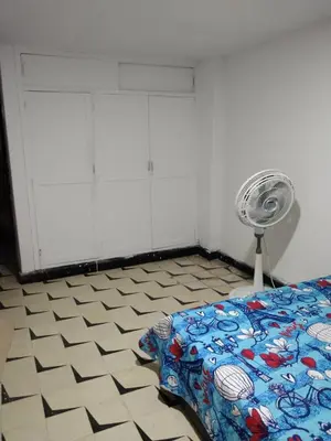 a bedroom with a bed and a fan on a tiled floor at Habitacion privada con servicios incluidos in Barranquilla
