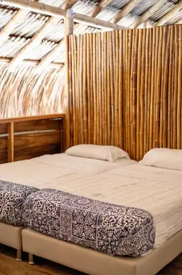 a bedroom with two beds and a wooden wall at Rincón del Mangle in San Onofre