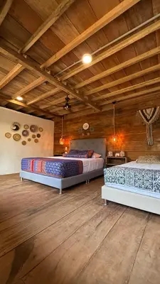 two beds in a large room with wooden ceilings at Rincón del Mangle in San Onofre